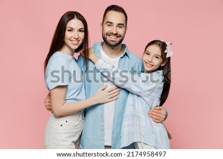 Young smiling fun parents mom dad with child kid daughter teen girl in blue clothes hugging father look camera isolated on plain pastel light pink background. Family day parenthood childhood concept