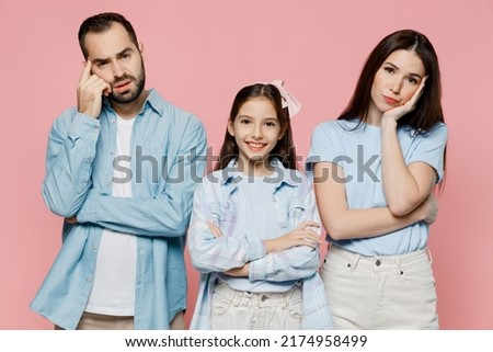 Young worried tired parents mom dad with child kid daughter teen girl in blue clothes prop up chin look camera isolated on plain pastel light pink background. Family day parenthood childhood concept