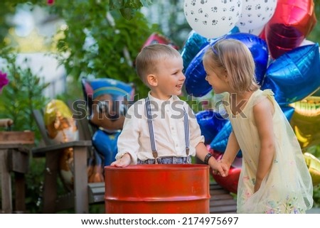 A little boy and a girl
 at a children's party. Children hold hands. Balloons in the background. The concept of children's parties.