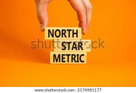 North star metric symbol. Concept words North star metric on wooden blocks on a beautiful orange table orange background. Businessman hand. Business finacial and north star metric concept. Copy space.