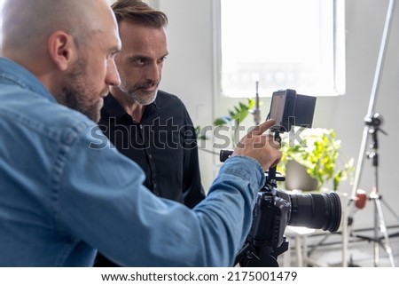 Director and Producer Working on Set. Reviewing Monitor Together as a Team. Behind the Scenes on Video Production Set for TV, Advertising or Movie.