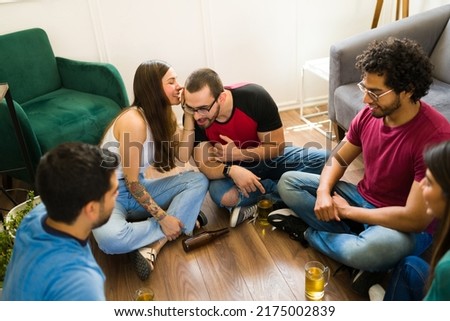 Gorgeous young woman telling a secret to friends during a truth or dare game during a party  Royalty-Free Stock Photo #2175002839