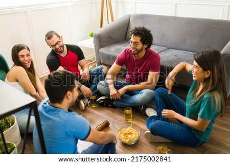 Excited friends in their 20s having a lot of fun and laughing while playing truth or dare during a party Royalty-Free Stock Photo #2175002841