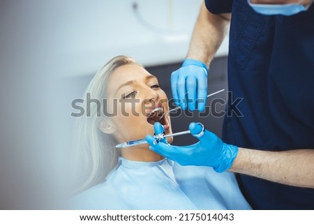 Overview of dental caries prevention.Woman at the dentist's chair during a dental procedure. Beautiful Woman smile close up. Healthy Smile. Dentist giving anesthesia to the patient