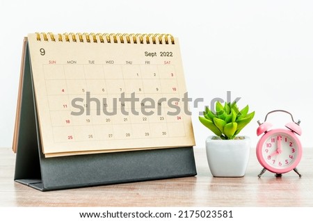 September 2022 green Desk calendar with pink alarm clock on wooden table. Royalty-Free Stock Photo #2175023581