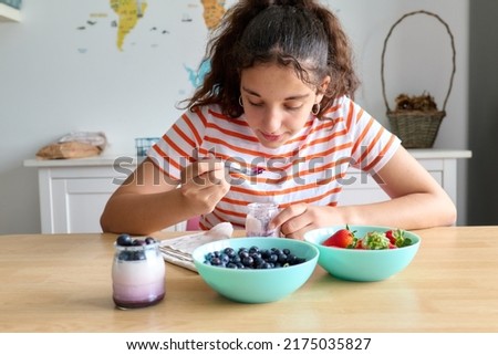 Teenage girl having a healthy breakfast with yogurt and fresh blackberries and strawberries, healthy eating concept Royalty-Free Stock Photo #2175035827