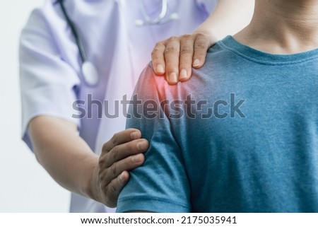 A man with shoulder pain goes to the doctor, The doctor diagnoses the patient's arm pain and shoulder pain. Concept of physical therapy and rehabilitation. Royalty-Free Stock Photo #2175035941