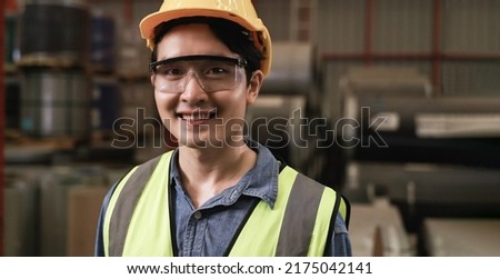 Portrait of happy professional Asian man worker wearing safety goggles and helmet standing smiling and looking at camera in the factory. Close up of handsome young male industry engineer in warehouse. Royalty-Free Stock Photo #2175042141