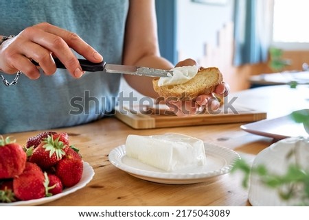 Woman making summer strawberry sandwich. Female hands spread stracchino cheese on bread for toast. Healthy eating, fruit dieting brunch. Royalty-Free Stock Photo #2175043089