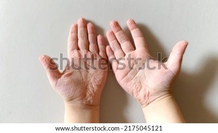 The photo palm child of three years , which wrinkled and shriveled due to the long stay in the water and swim , pink palm on a blur background. Royalty-Free Stock Photo #2175045121