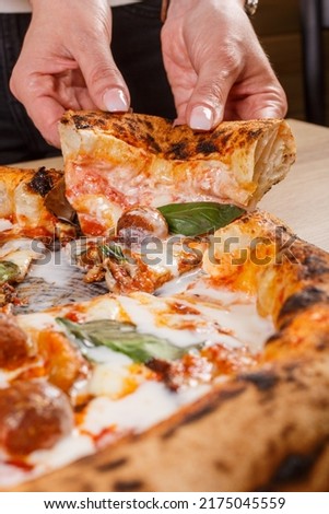 Pizza Napoletana Gourmet with meatballs, fresh basil, eggplant parmigiana and cream cheese in the hands of a customer