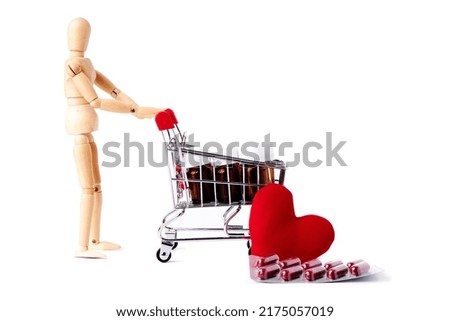 Dummy pushing shopping cart full of medicine jars together with pills and a red heart. Medicine and health concept