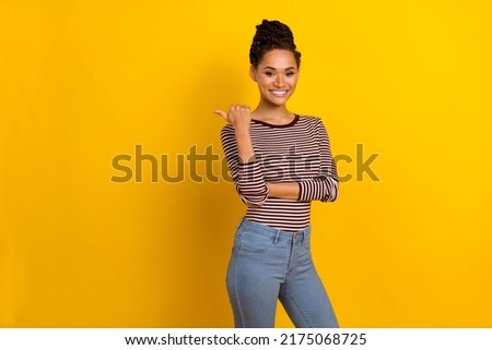 Photo of pretty positive person indicate thumb finger empty space offer isolated on yellow color background