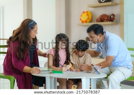 Happy Asian family with mother father daughter and son draw together in living room at home for they education when spend their family time.