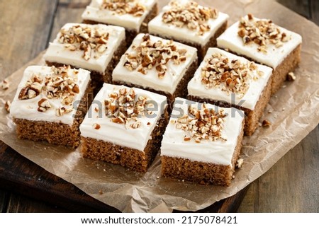 Carrot or pumpkin spiced cake bars with cream cheese frosting and pecan nuts with caramel syrup
