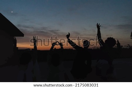 Silhouette of many friends watching sunset with hand posts