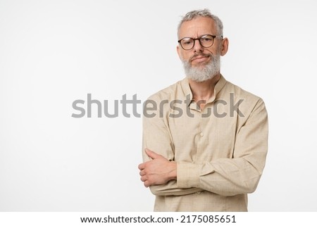 Sad offended disappointed caucasian mature middle-aged man in beige shirt and glasses feeling depression guilt negative emotions isolated in white background Royalty-Free Stock Photo #2175085651