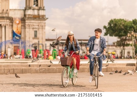 Portrait of young Latin couple with bikes in a downtown park. Royalty-Free Stock Photo #2175101415