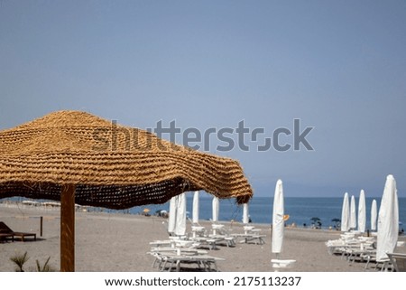 Chairs and an umbrella on the beach made of natural materials. Beach umbrellas.Tropical gazebo on an amazing beach with a palm tree.