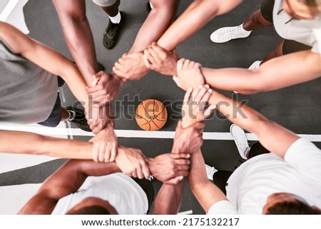Athletes showing trust and standing united. Men expressing team spirit with their hands joined huddling at a basketball game. Sportsmen holding wrists in huddle for support and unity at sports match.