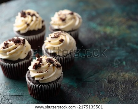 Chocolate cupcakes with cream and grated chocolate. Isolated on a dark background. Holiday, birthday. There are no people in the photo. There is free space to insert.