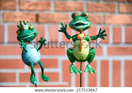 Kermett similar frog sculpture that Dominating with his princess in the garden outside the building. Green frogs against background of red bricks