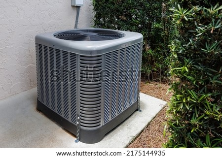 Modern HVAC air conditioner unit on concrete slab outside of house.  Royalty-Free Stock Photo #2175144935