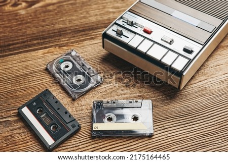 Compact cassette tapes and cassette recorder on wooden table. Retro music style. 80s music party. Vintage style. Analog equipment. Stereo sound. Back to the past Royalty-Free Stock Photo #2175164465