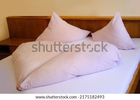 bright hotel room on the bed, heart-shaped white blanket, two pillows, cotton bed linen, the concept of healthy sleep, insomnia problems, a cozy stay in a hotel