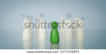 Green wood figure with happy face standing out from the crowd of different people. Individuality, Introvert, Not care when someone is talking, Unique human shape, Leadership,  Human resource.  Royalty-Free Stock Photo #2175196895