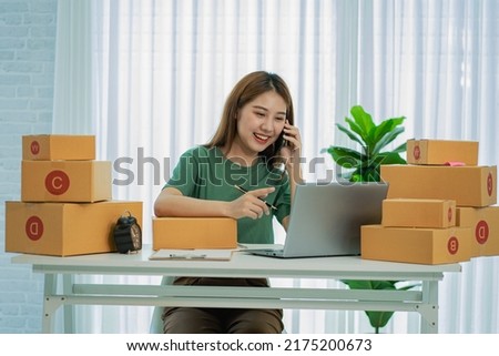 Independent SME Small Business Entrepreneur Portrait of an Asian woman working at home with a laptop taking orders and Online Marketing Packaging Shipping Boxes eCommerce business idea