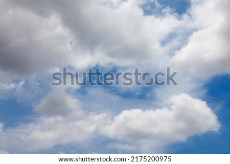 Picture of a turquoise sky with black and white clouds near the rain.