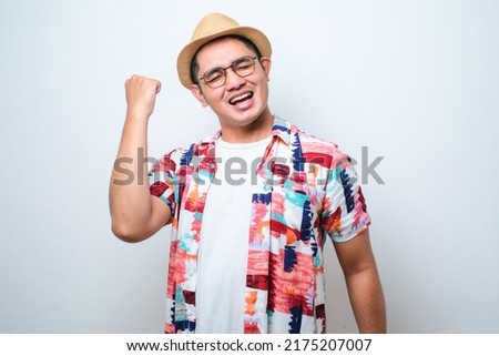 Young asian man wearing casual beach style shirt standing over isolated white background very happy and excited doing winner gesture with arms raised, smiling and screaming for success.