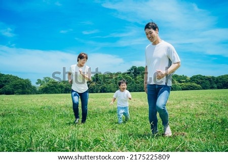 Parents and their child running around the meadow Royalty-Free Stock Photo #2175225809