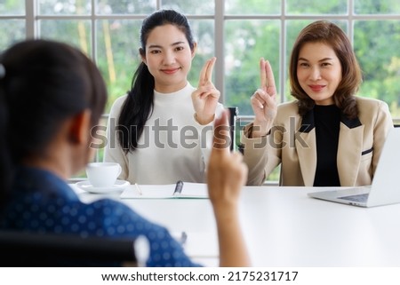 Deaf translator teaching two businesswomen to use and understand hand language sign.