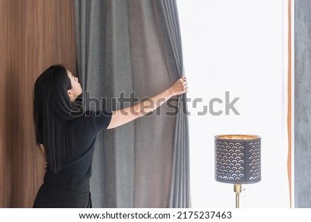 Maid housewife woman working chores housekeeping cleaning room arrange window curtains at home or hotel. Royalty-Free Stock Photo #2175237463