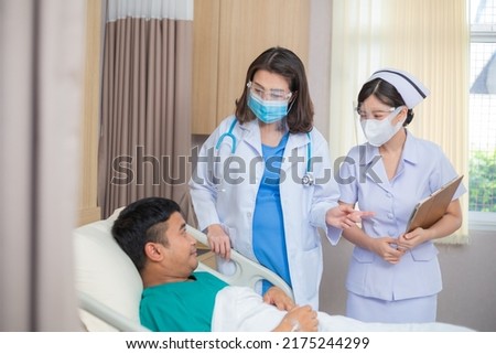 Asian female doctor and nurse wearing protective mask visit male patient in the hospital ward. medical staff examined and checking on sick man, healthcare insurance concept