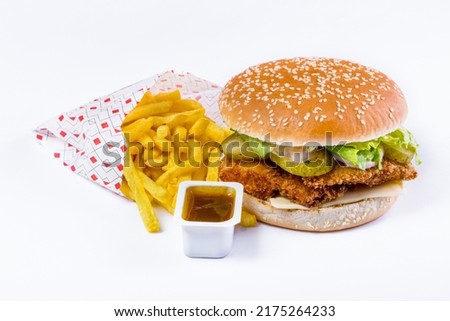 Burger with sesame bun, cutlet, salad, white sauce, pickled cucumbers and cheese with fries and sauce on a white background. Horizontal orientation