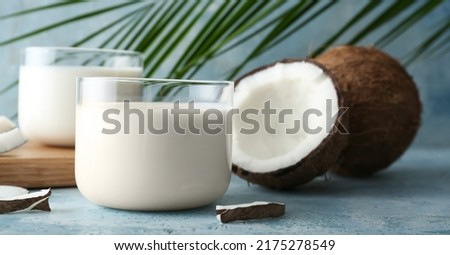 Glasses of fresh coconut milk on blue background