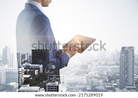 Business technology concept with businessman using modern digital tablet on city skyline background, double exposure