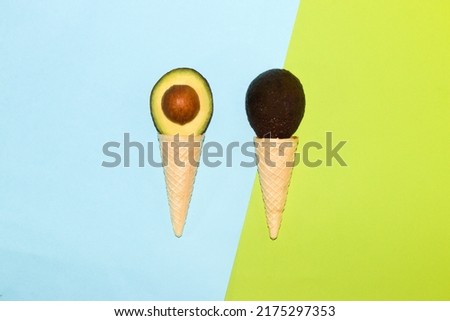 creative avocado ice creams on a pastel blue-green background, two ice cream cones with avocado slices, trendy background, summer design