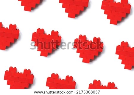 Red hearts from toy blocks isolated on white background, minimal geometric pattern from blocks, shape heart from child construction. Love game concept, Valentine Day card, top view repit pattern