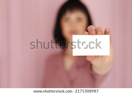 Businesswoman showing and handing a blank business card. Hands holding a white business visit card, gift, ticket, pass, present close up on blurred blue background. Copy space