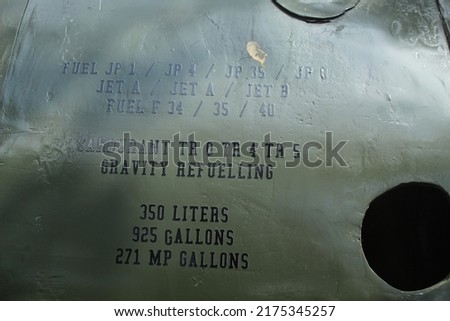 instructions on the body of a military aircraft on a faded blue background.