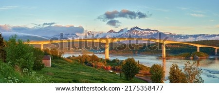 Landscape view of Saltstraumen in Nordland, Norway in winter. Scenery of infrastructure and bridge over a river and stream with snow capped mountains in the background. Traveling abroad and overseas