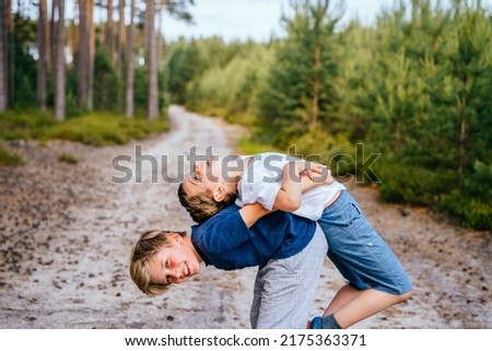 Two boys, friendsor brothers wrestle, compete, play active games in the pine forest on vacation.