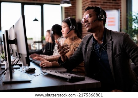 Reception secretary answering client phone call at customer service, helping people at call center support. Male receptionist giving telemarketing assistance on phone helpline in office. Royalty-Free Stock Photo #2175368801