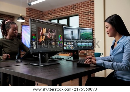 Creative agency professional video editor sitting at desk while using specialized software to enhance movie frames quality. Expert videographer improving film footage quality. Royalty-Free Stock Photo #2175368893