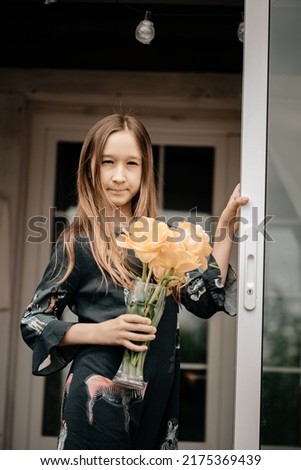 Real emotions on the face of a happy child. Ideas for a photo shoot girl on the balcony. A beautiful girl with flowers in her hands. Fervent emotions.