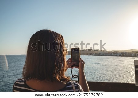 woman's hand holding smartphone to taking sunset photo on the beach. mobile phone with view on screen at sunset